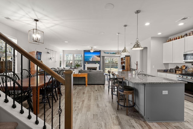 kitchen featuring sink, stainless steel appliances, a center island with sink, and light stone countertops