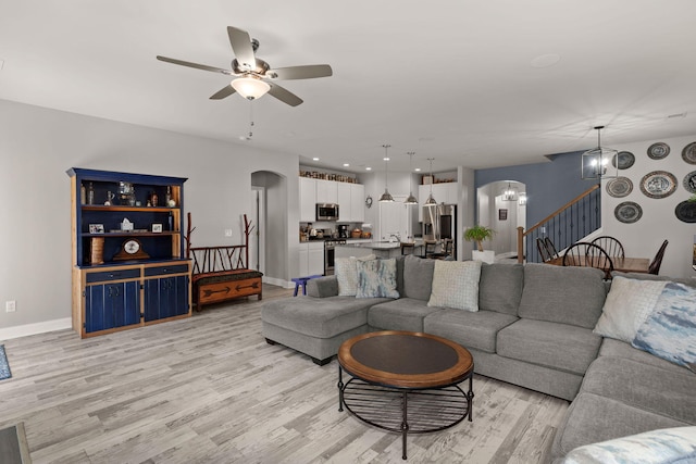 living room featuring light wood-type flooring and ceiling fan with notable chandelier