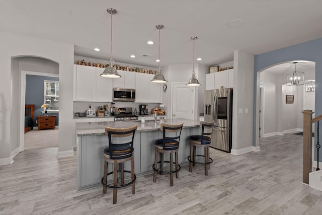 kitchen featuring a center island with sink, pendant lighting, white cabinetry, and stainless steel appliances