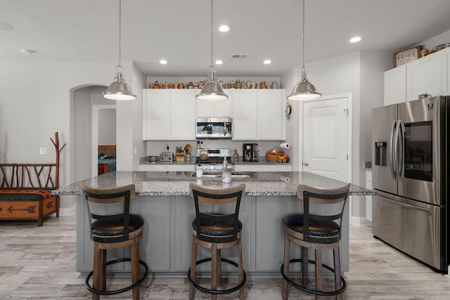 kitchen featuring white cabinets, pendant lighting, stone counters, and appliances with stainless steel finishes