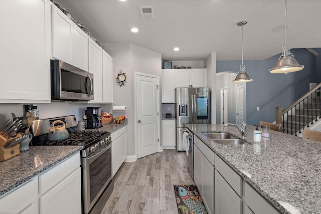 kitchen with pendant lighting, sink, white cabinetry, and appliances with stainless steel finishes