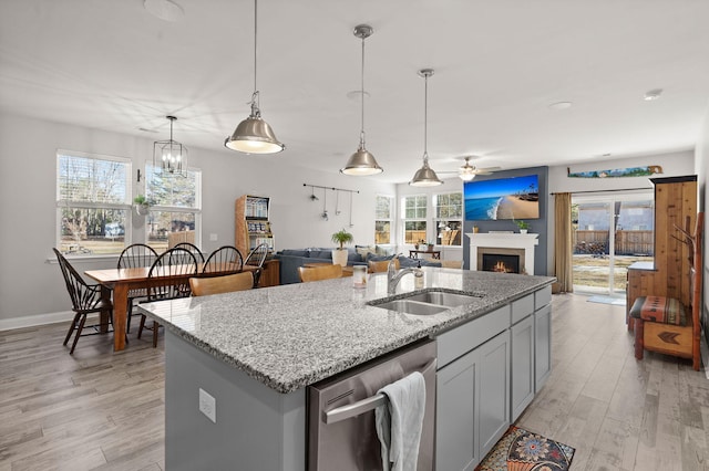 kitchen with sink, a kitchen island with sink, decorative light fixtures, and dishwasher