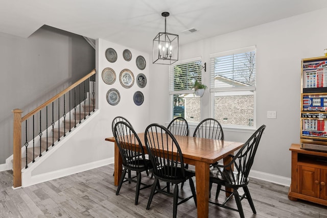 dining space with hardwood / wood-style flooring and an inviting chandelier