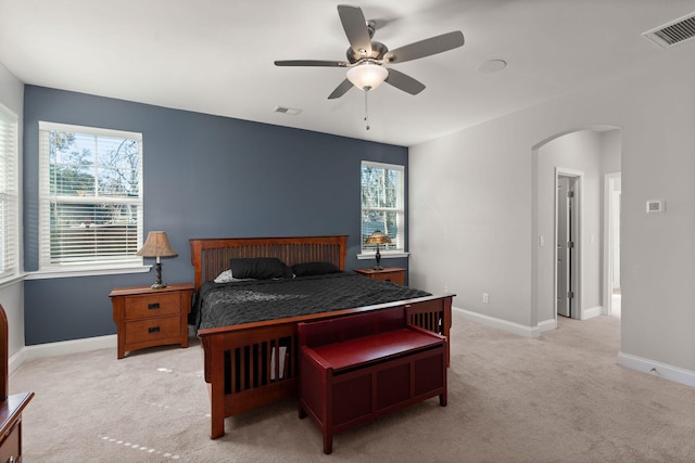 bedroom featuring ceiling fan, light colored carpet, and multiple windows