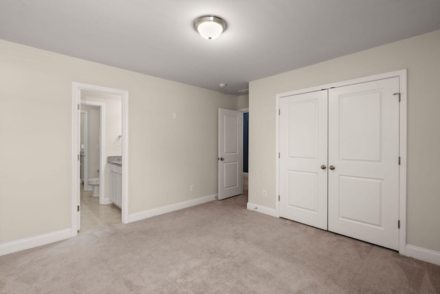 unfurnished bedroom featuring connected bathroom, a closet, and light carpet