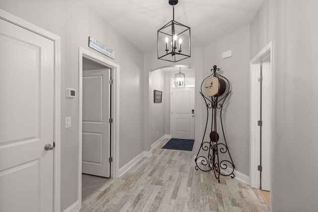 doorway to outside with a chandelier and light hardwood / wood-style flooring