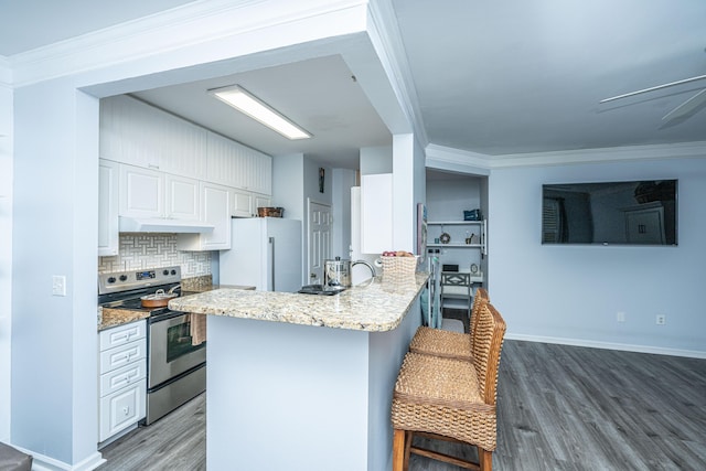 kitchen featuring electric stove, crown molding, freestanding refrigerator, white cabinetry, and a kitchen breakfast bar