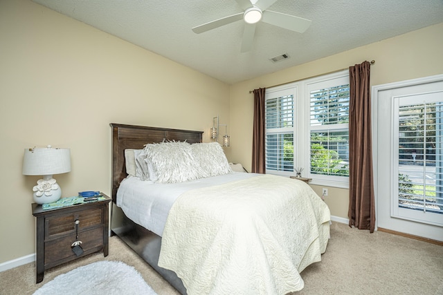 bedroom featuring light carpet, a textured ceiling, visible vents, and baseboards