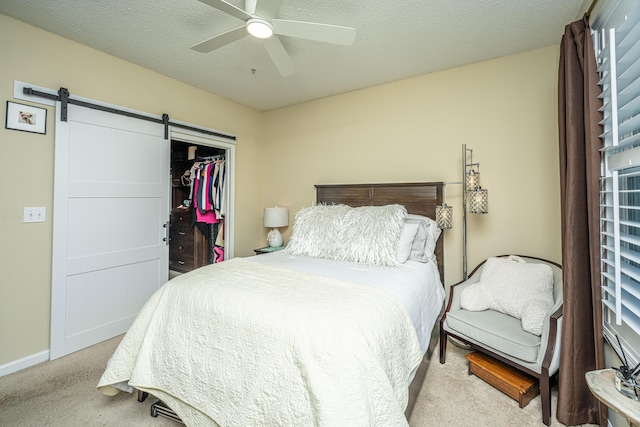 bedroom featuring a barn door, a closet, a textured ceiling, and light colored carpet