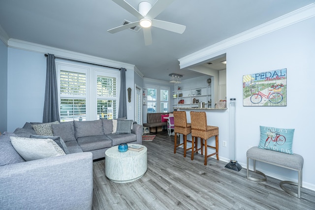 living room featuring ceiling fan, crown molding, baseboards, and wood finished floors