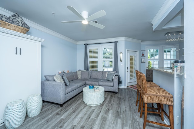 living area with ceiling fan, wood finished floors, visible vents, and crown molding