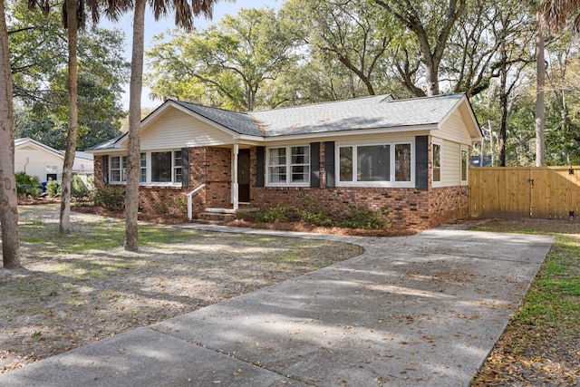 view of front of house with brick siding, driveway, and fence