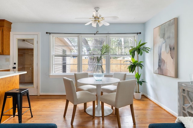 dining area with light wood-style flooring, baseboards, and ceiling fan