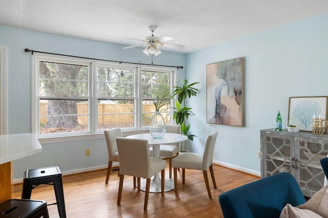 dining space with wood finished floors, a ceiling fan, and baseboards