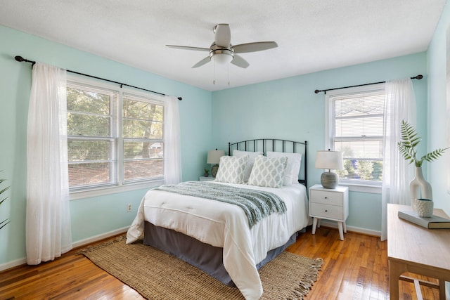 bedroom with hardwood / wood-style floors, baseboards, and ceiling fan