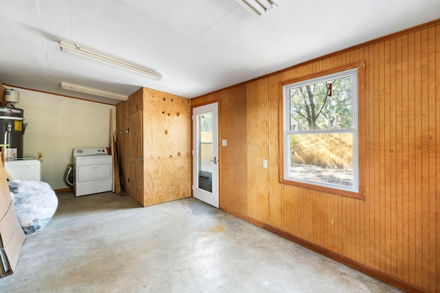 interior space with washer and clothes dryer, electric water heater, wooden walls, baseboards, and concrete flooring