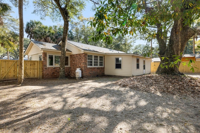 rear view of house with brick siding, fence, and a gate