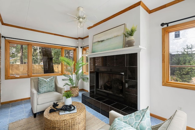 living area with ceiling fan, baseboards, a healthy amount of sunlight, and ornamental molding