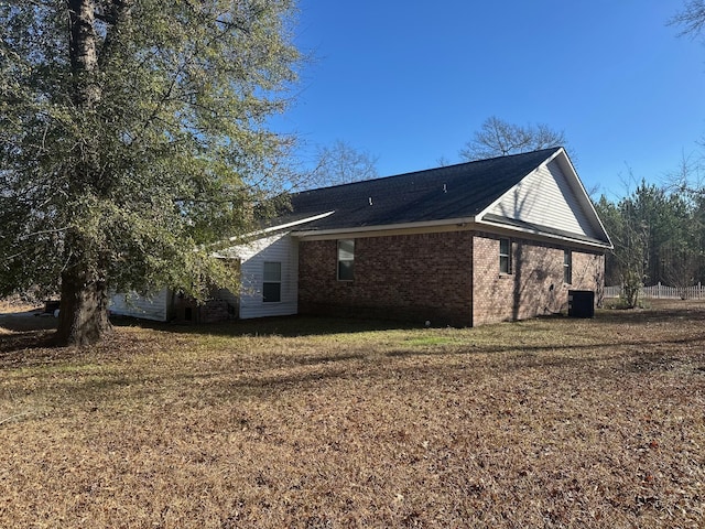 view of side of property with a lawn and cooling unit