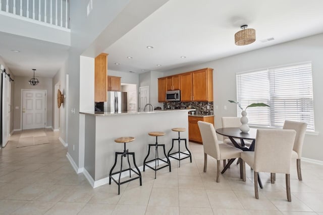 7511 Hawks Cir, Hanahan, SC 29410 - kitchen featuring stainless steel appliances, backsplash, a breakfast bar, a peninsula, and light tile patterned flooring
