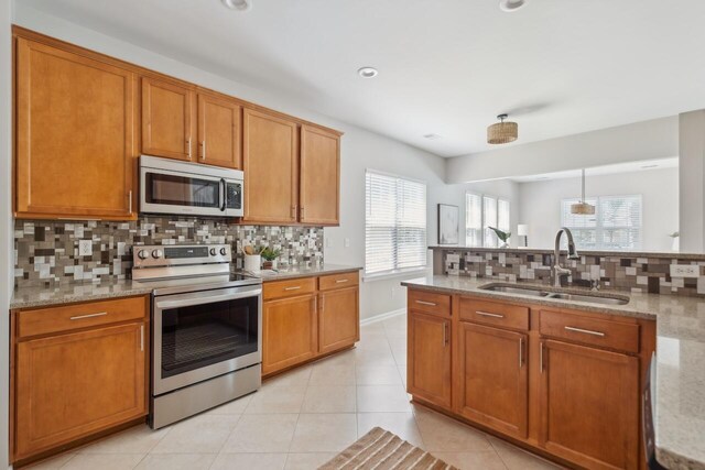 7511 Hawks Cir, Hanahan, SC 29410 - kitchen with appliances with stainless steel finishes, backsplash, brown cabinetry, and recessed lighting