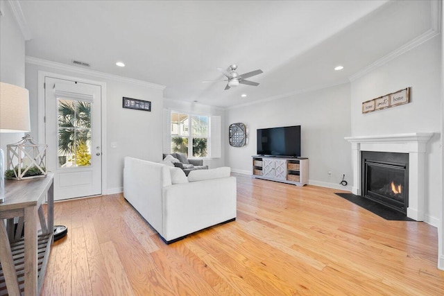 living area featuring ornamental molding, light wood finished floors, a fireplace with flush hearth, and baseboards