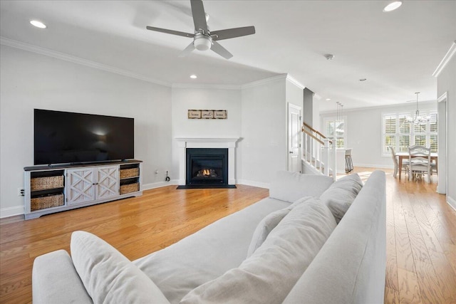 living room featuring crown molding, baseboards, wood finished floors, and recessed lighting