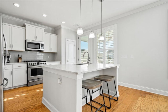 kitchen featuring a center island with sink, decorative backsplash, appliances with stainless steel finishes, crown molding, and a sink