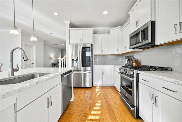 kitchen featuring a sink, white cabinetry, ornamental molding, appliances with stainless steel finishes, and decorative backsplash