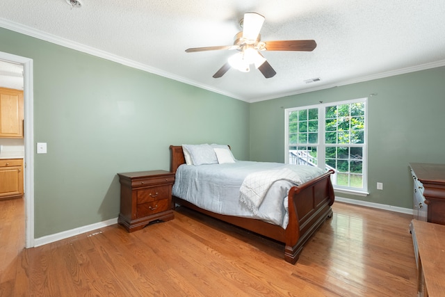 bedroom featuring ceiling fan, light hardwood / wood-style floors, a textured ceiling, and crown molding