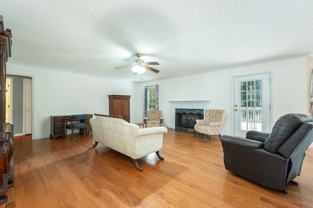 living room featuring a healthy amount of sunlight, ceiling fan, light hardwood / wood-style flooring, and a textured ceiling