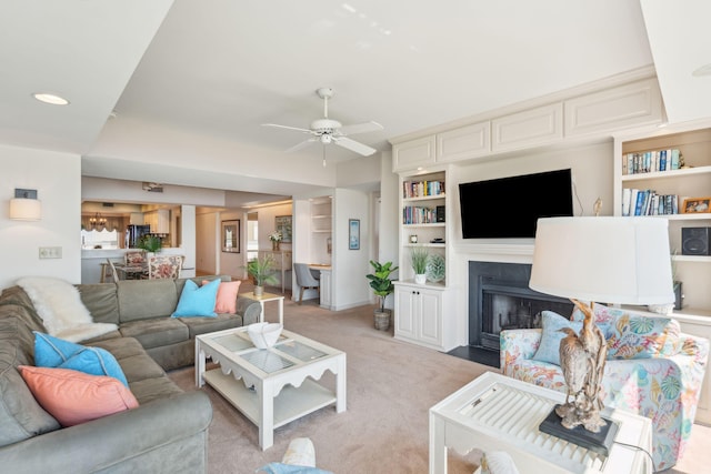 carpeted living room featuring ceiling fan and built in shelves