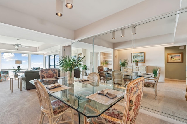 carpeted dining room featuring ceiling fan and a tray ceiling