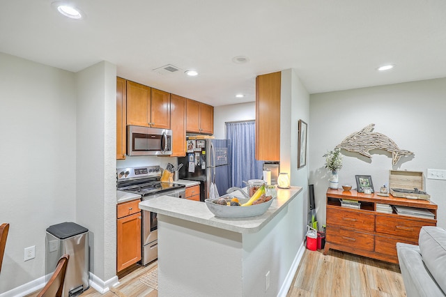 kitchen featuring kitchen peninsula, stainless steel appliances, and light wood-type flooring