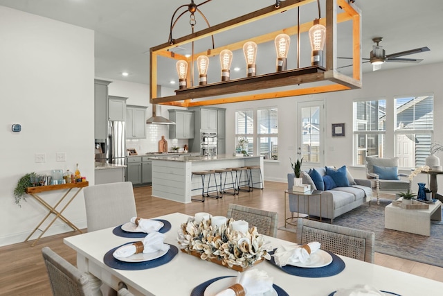 dining room with light wood-type flooring, baseboards, a ceiling fan, and a wealth of natural light