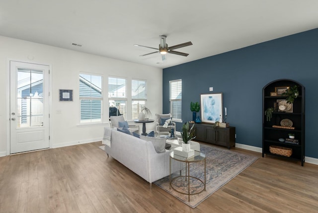 living room featuring ceiling fan, baseboards, and wood finished floors