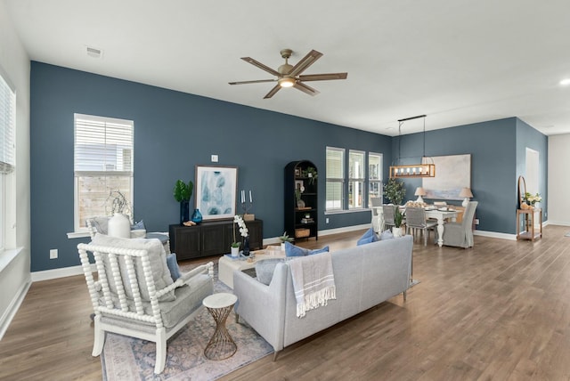 living area featuring visible vents, ceiling fan, baseboards, and wood finished floors