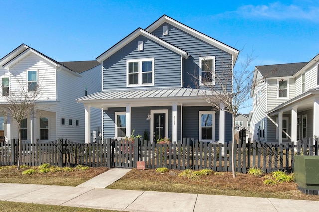 view of front facade featuring a standing seam roof, metal roof, a porch, and a fenced front yard