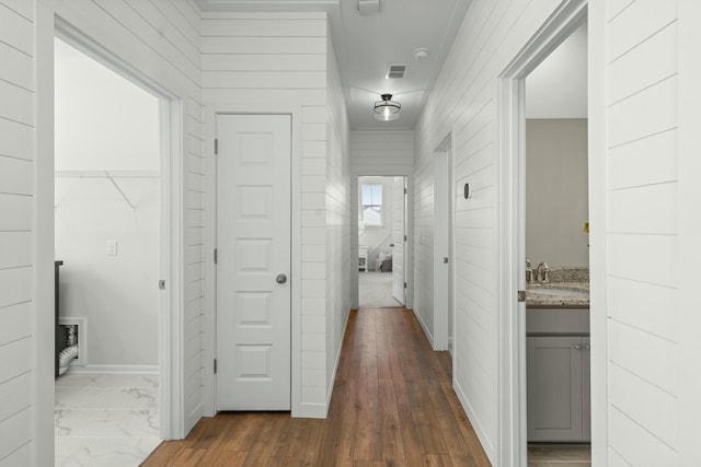 hall featuring marble finish floor, visible vents, a sink, and baseboards