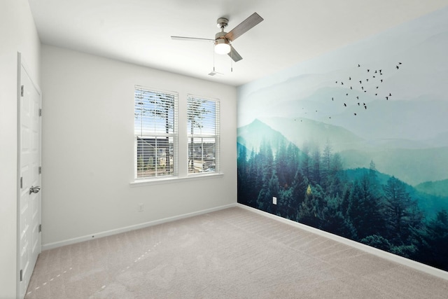 carpeted spare room featuring baseboards and a ceiling fan