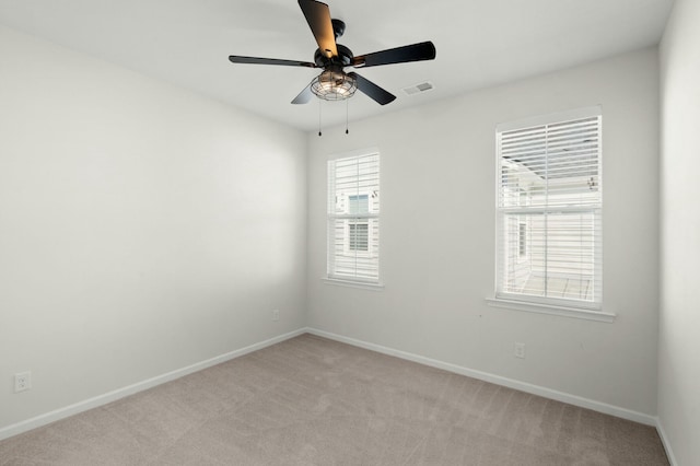 spare room with baseboards, a ceiling fan, visible vents, and light colored carpet