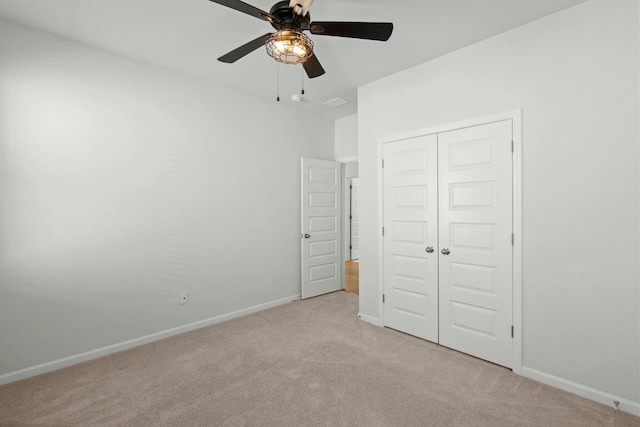 unfurnished bedroom with baseboards, ceiling fan, a closet, and light colored carpet