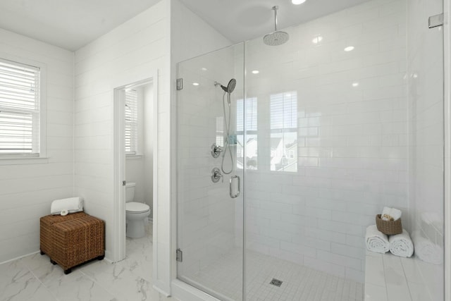 bathroom featuring marble finish floor, a shower stall, and toilet