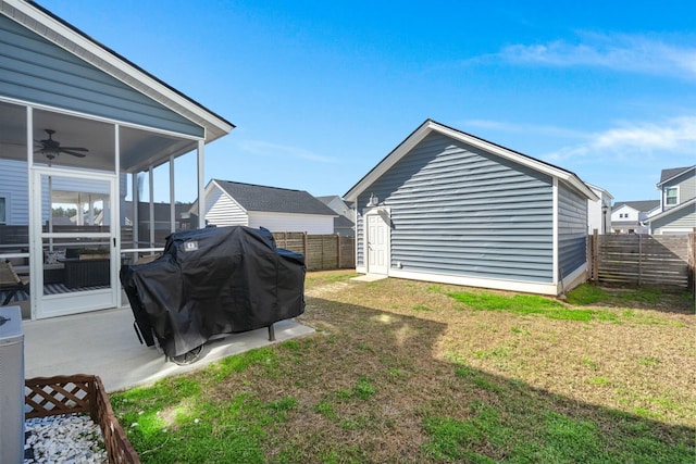 view of yard with a sunroom, a fenced backyard, a ceiling fan, and an outdoor structure