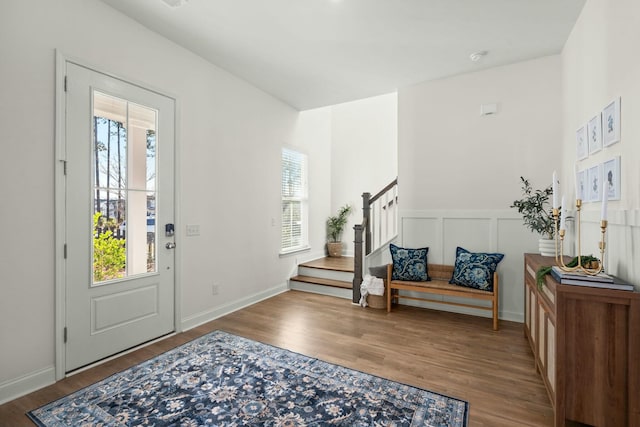 entryway featuring a wainscoted wall, stairway, wood finished floors, and a decorative wall