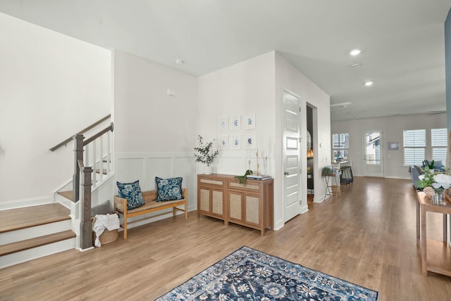 foyer with a decorative wall, stairway, wood finished floors, and recessed lighting