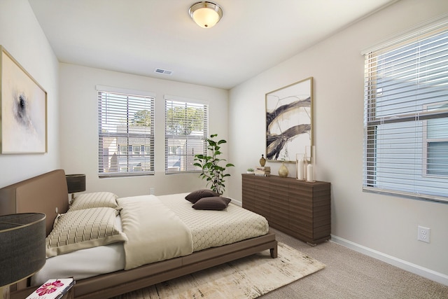 bedroom with light colored carpet, visible vents, and baseboards