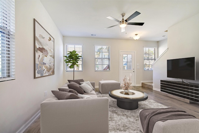 living room with stairs, dark wood finished floors, a ceiling fan, and baseboards