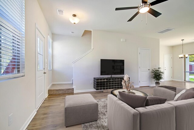 living room with ceiling fan with notable chandelier and hardwood / wood-style floors