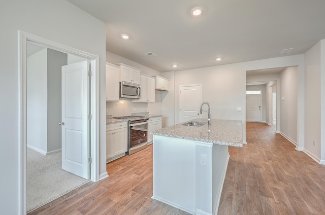 kitchen with white cabinets, a kitchen island with sink, appliances with stainless steel finishes, and sink